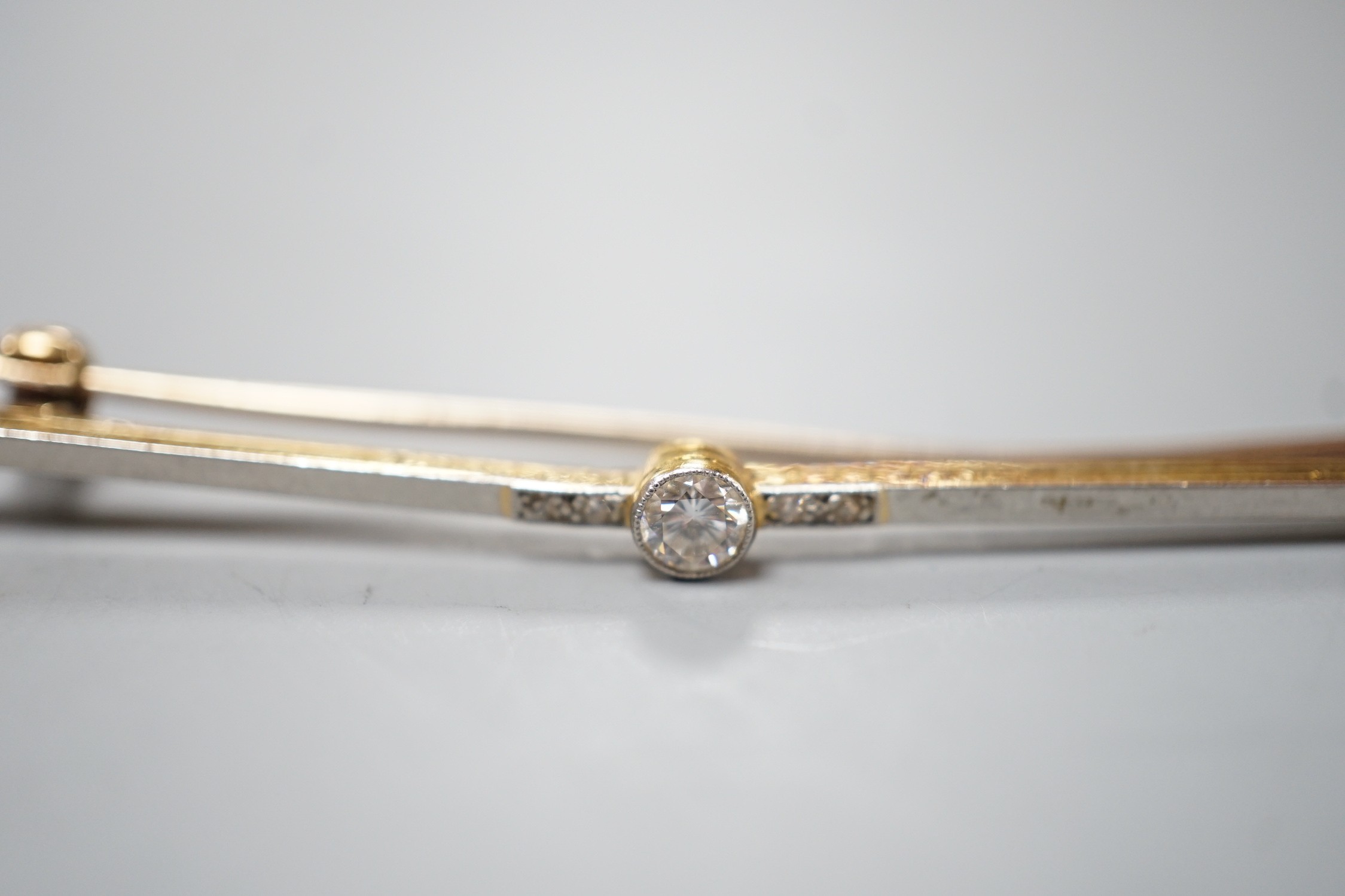 An Edwardian 15ct and single stone diamond set bar brooch, with diamond chip setting, 57mm, gross weight 3.1 grams.